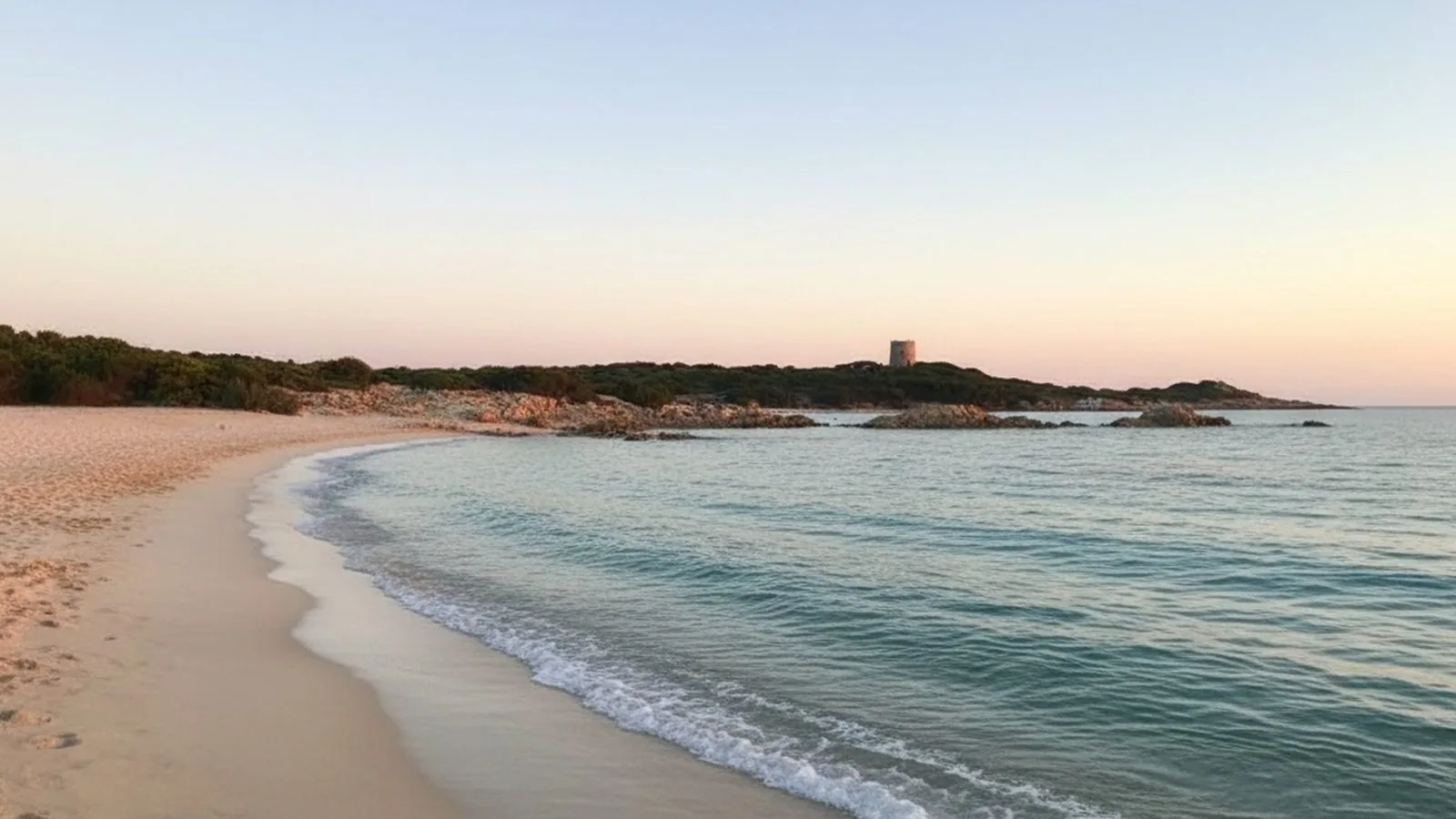 Vignola Mare: la spiaggia di sabbia chiara al tramonto con la torre sullo sfondo